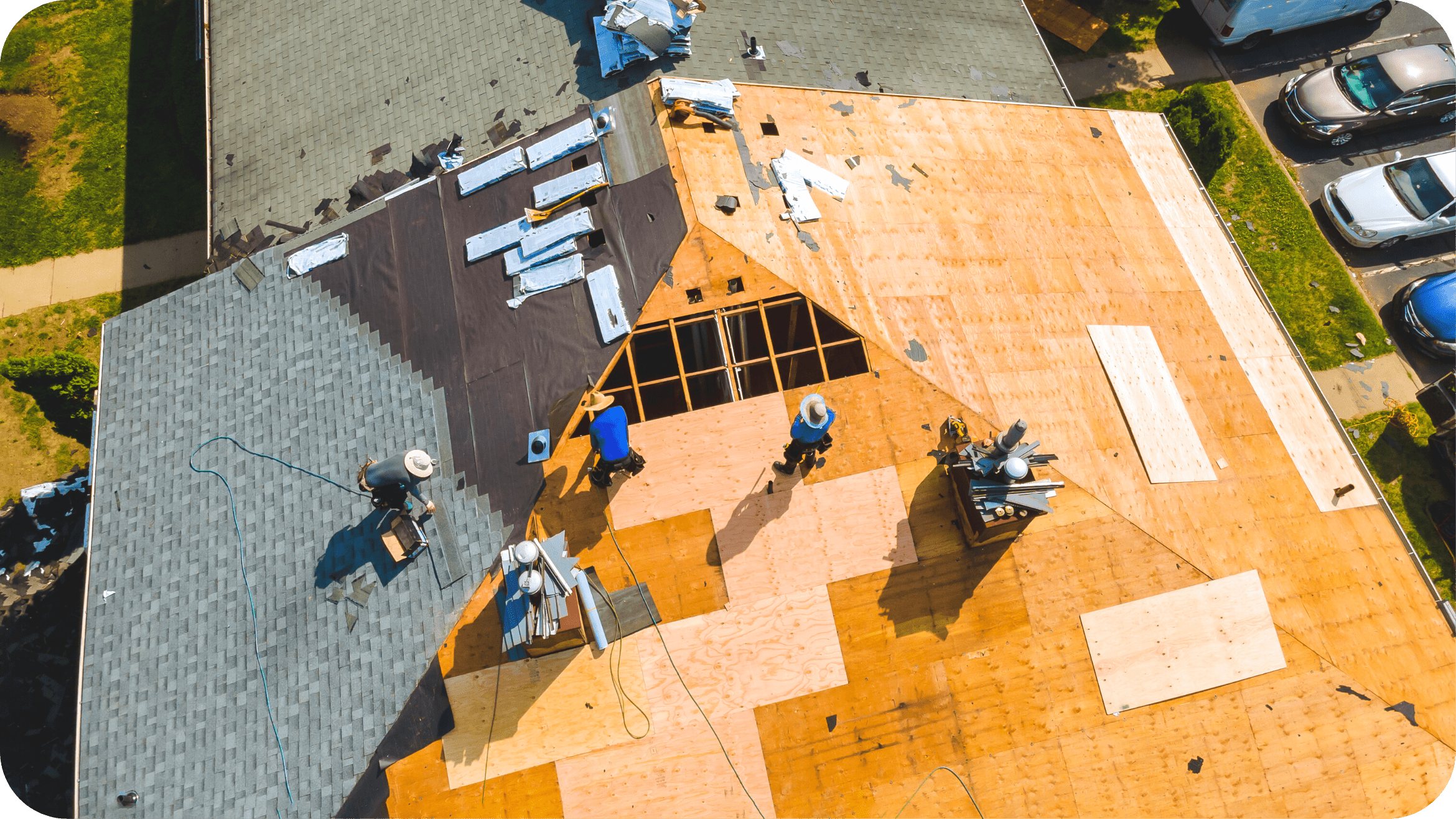 Aerial view of three roofers replacing an asphalt shingle roof on a Huntsville home