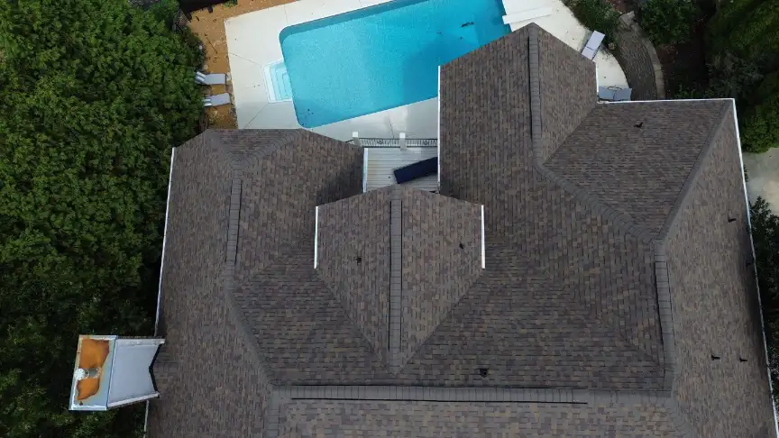 Brown shingle roof completed on a home with a tree-shaded backyard pool