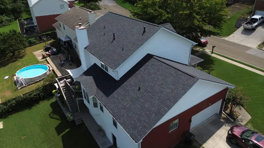 Large suburban home with a finished dark gray shingle roof and backyard deck