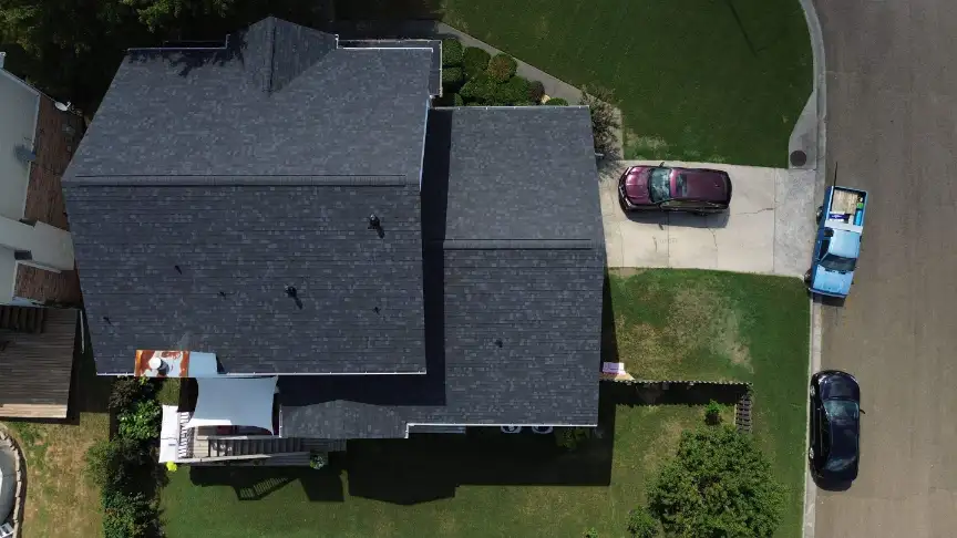 Completed dark roof on a home with a driveway and wide green lawns