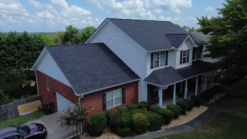 White and brick two-story home with a finished black roof and covered porch