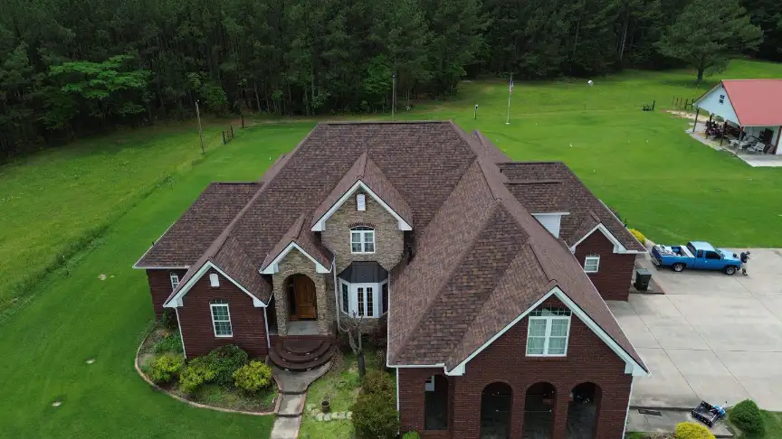 Large brick estate featuring a durable brown roof installed by a top Huntsville roofing company.