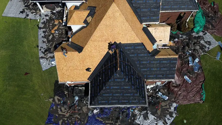 Storm-worn shingles cleared off a Scottsboro roof onto tarps spread across the yard