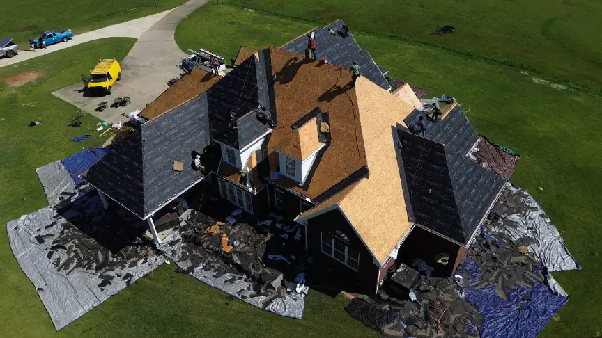 Huntsville roof replacement team using protective tarps to safeguard landscaping during installation.