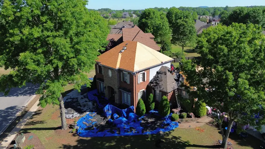 Huntsville roofing company utilizing extensive ground tarps to protect yard and shrubs during replacement.