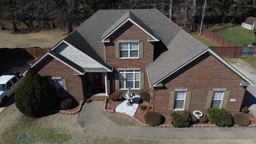 Elegant two-story brick home with landscape fountain and freshly installed architectural shingles.