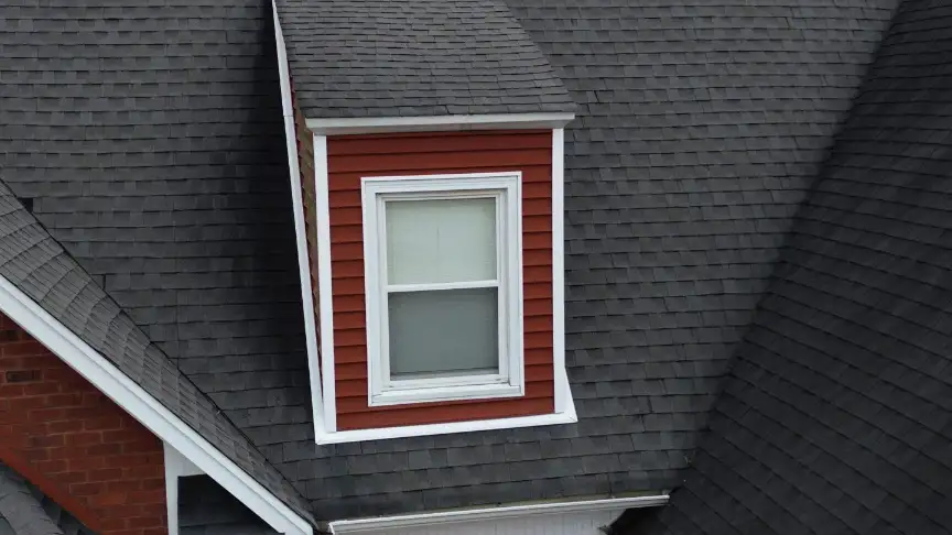 Close-up of dormer window and flawless flashing work on a dark grey shingled roof.