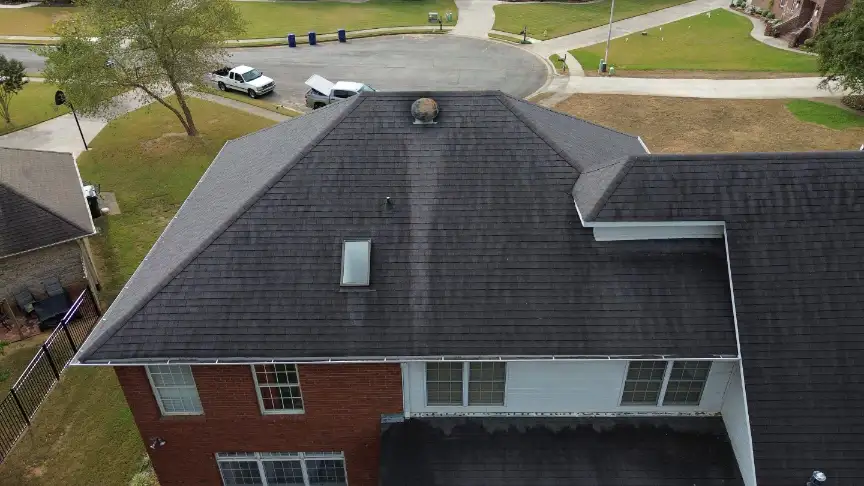 New dark gray roof with a skylight and chimney on a quiet street