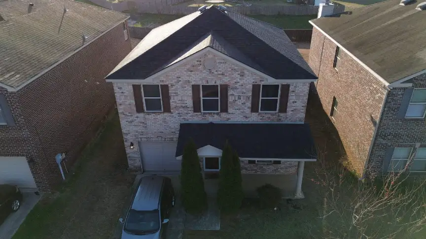 Two-story brick home with black shutters and a freshly finished roof