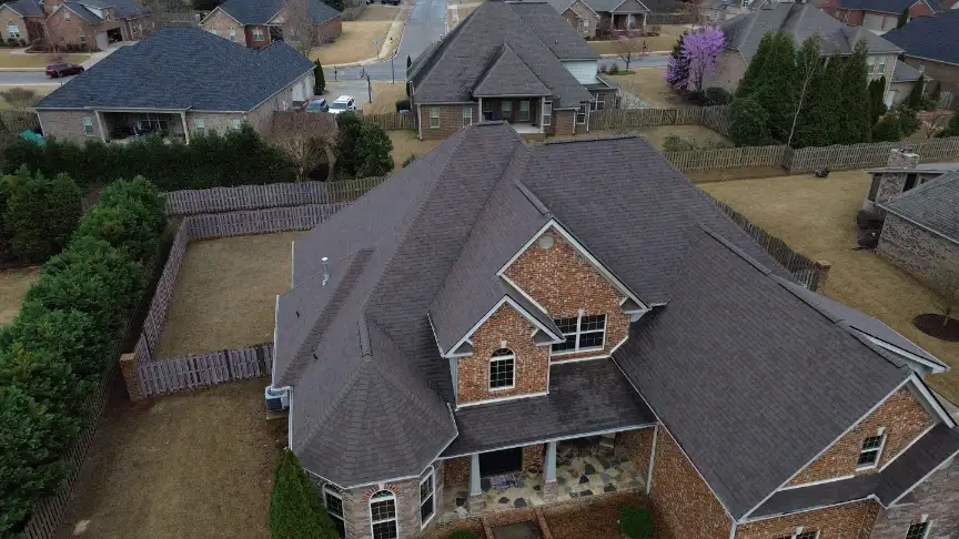 Two-story brick suburban home boasting a pristine new grey roof replacement.