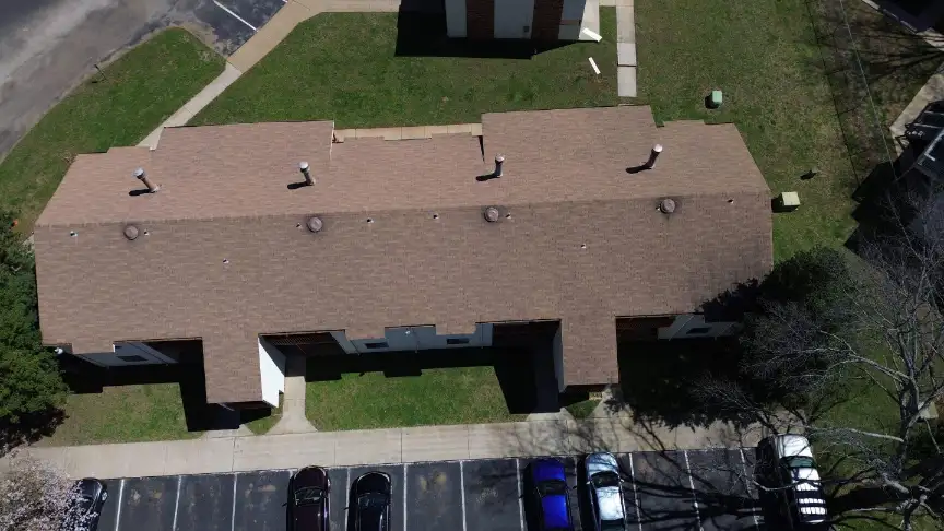 Commercial roofing contractors completing a large brown shingle roof for a multi-unit building in Huntsville.