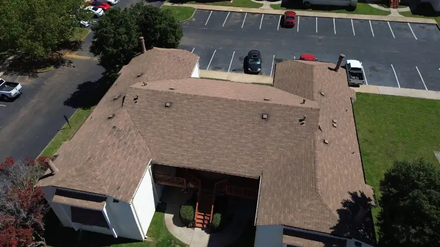 Aerial view of a building with brown shingle roofing and white exterior walls