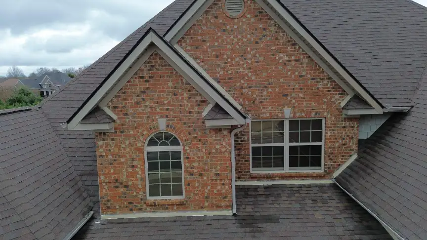 Steep dark shingle roof finished above an arched brick entry