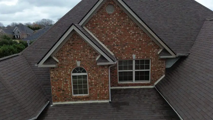 New dark gray shingle roof on a brick house on an overcast day