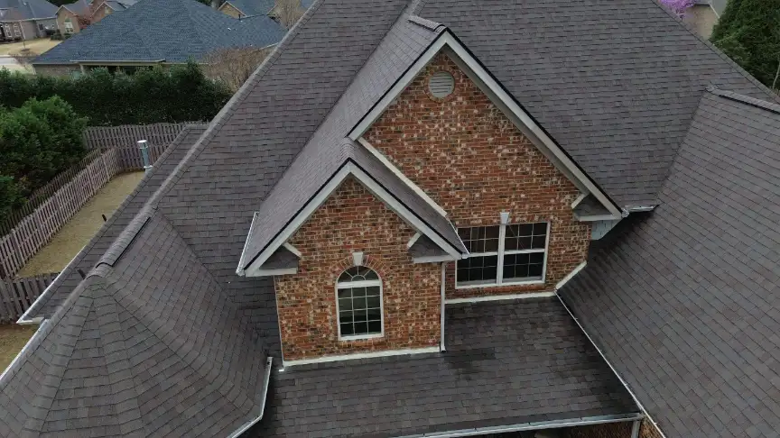 Completed dark gray roof with dormers and arched windows on a brick home