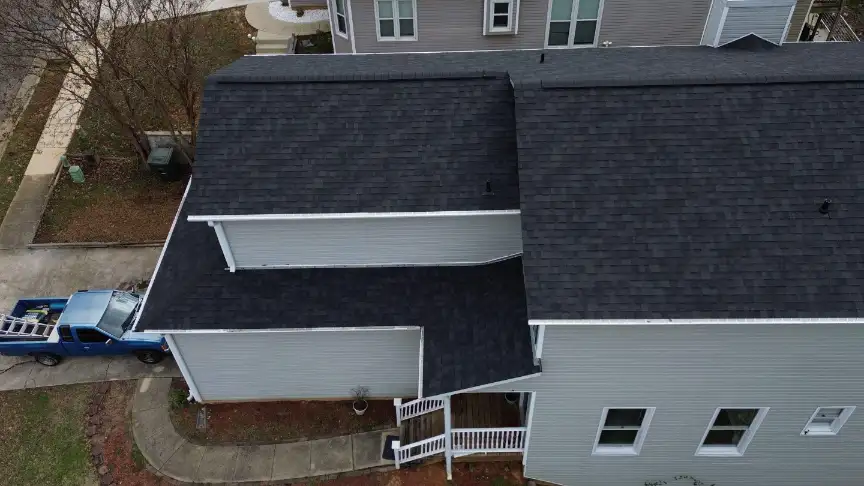 Finished dark roof on a gray-sided home with a truck in the drive