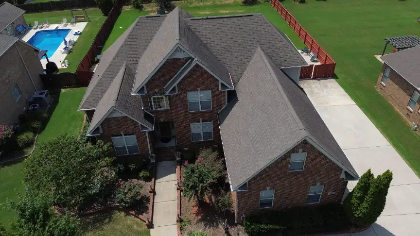 Completed gray roof on a two-story brick home with a backyard pool